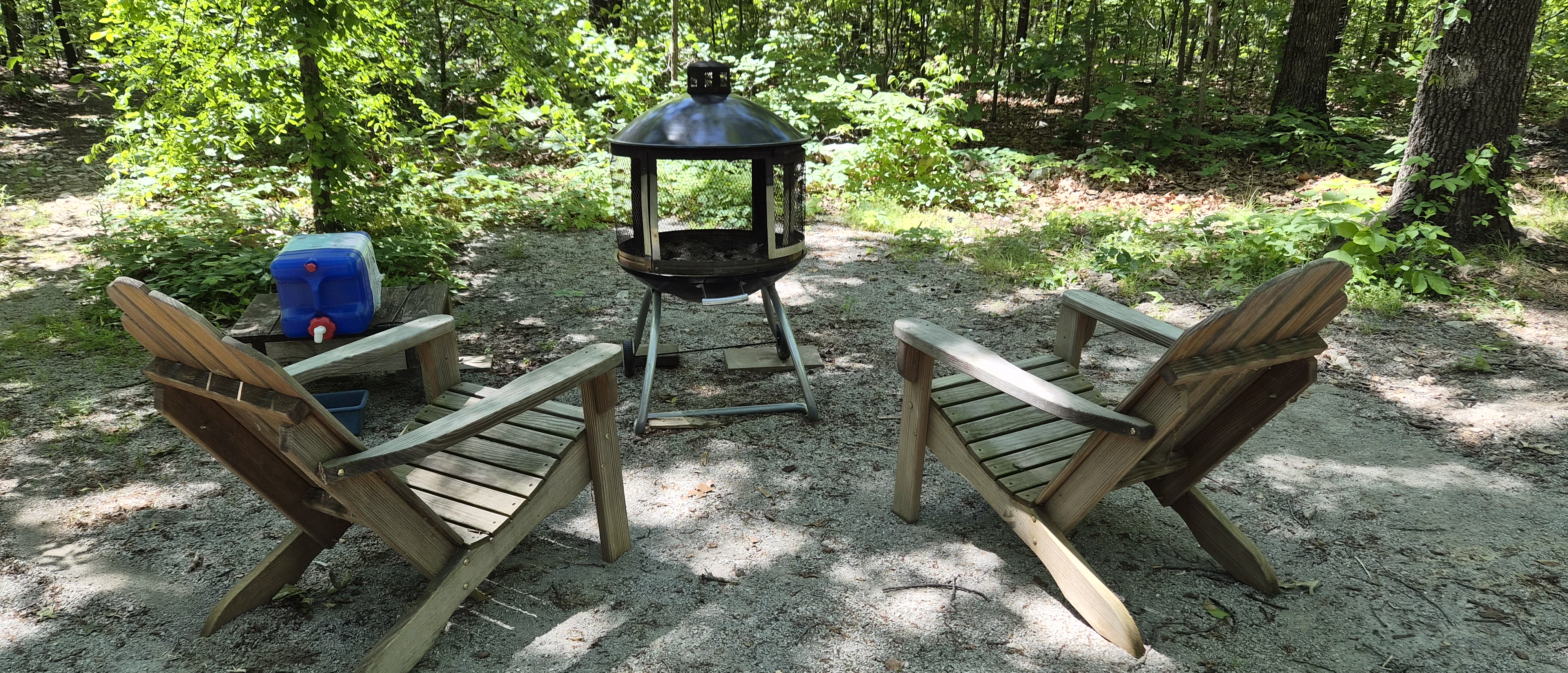 Fire pit and outdoor chairs in a wooded clearing